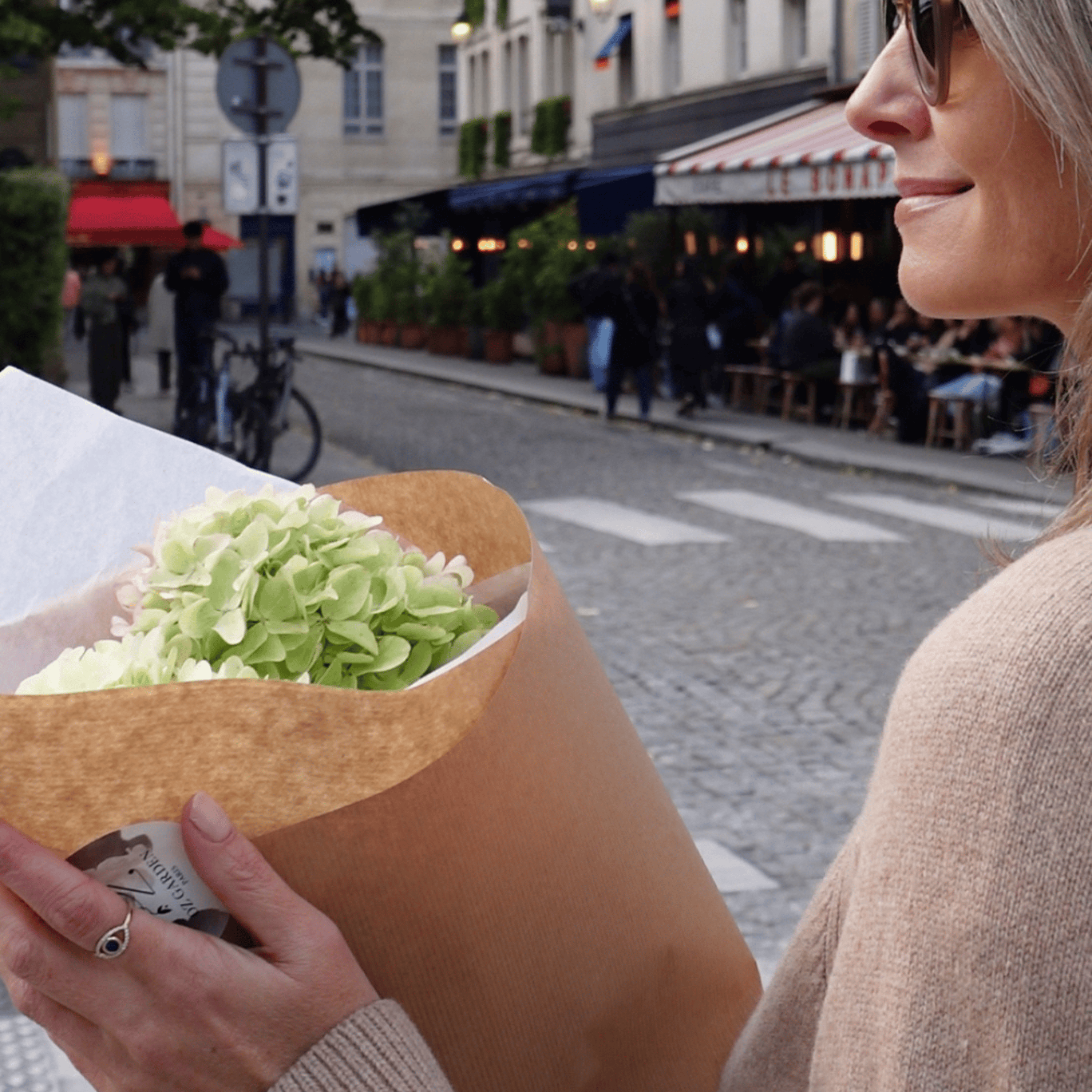 Louise Stokes, Founder of Loulerie, on a Parisien street carrying a bunch of fresh hydrangeas