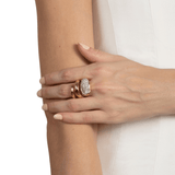 Close-up of a hand wearing gold coil design ring with a white background