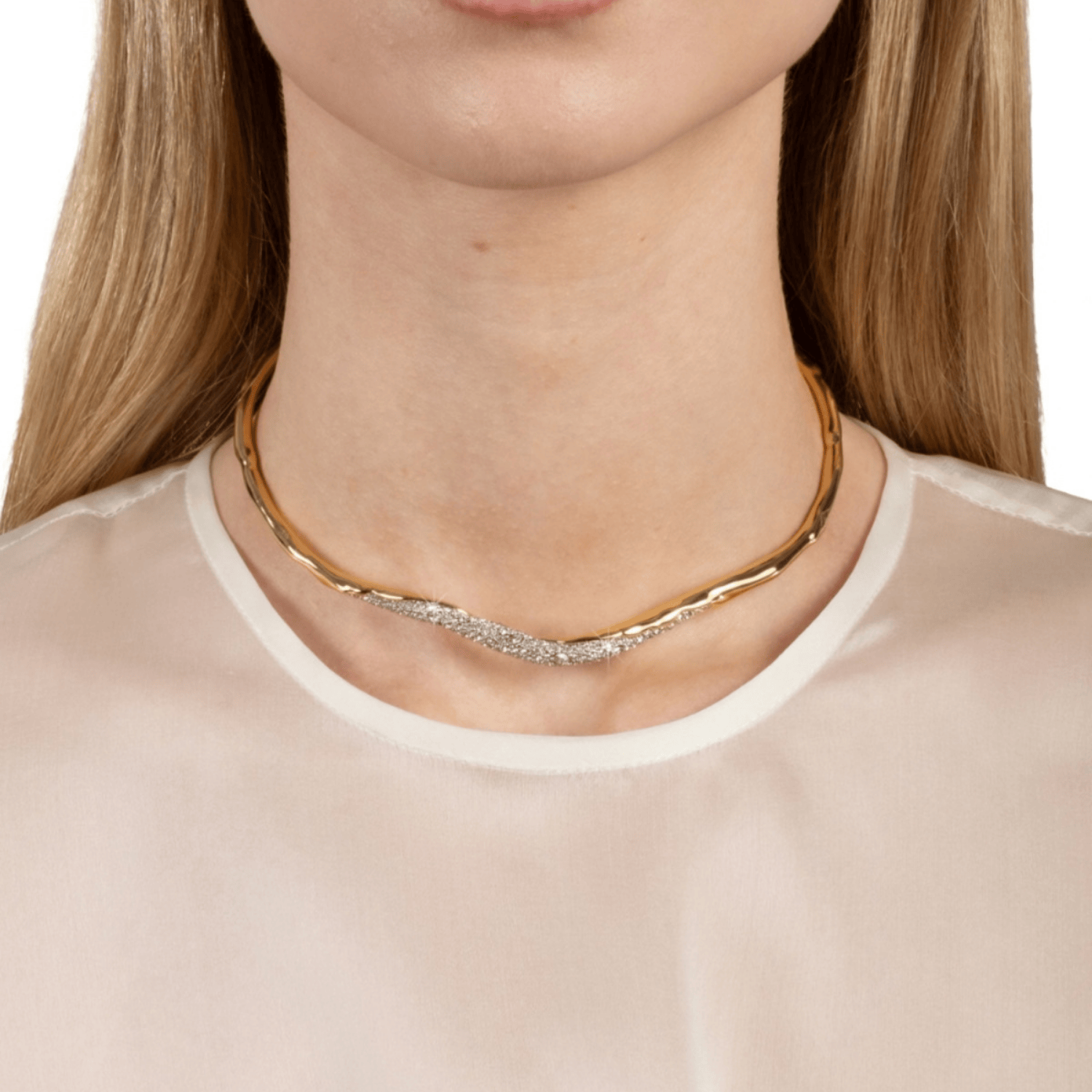A close-up of a model's neck wearing a delicate wavy gold necklace with a pavé diamond center, paired with a light beige blouse.