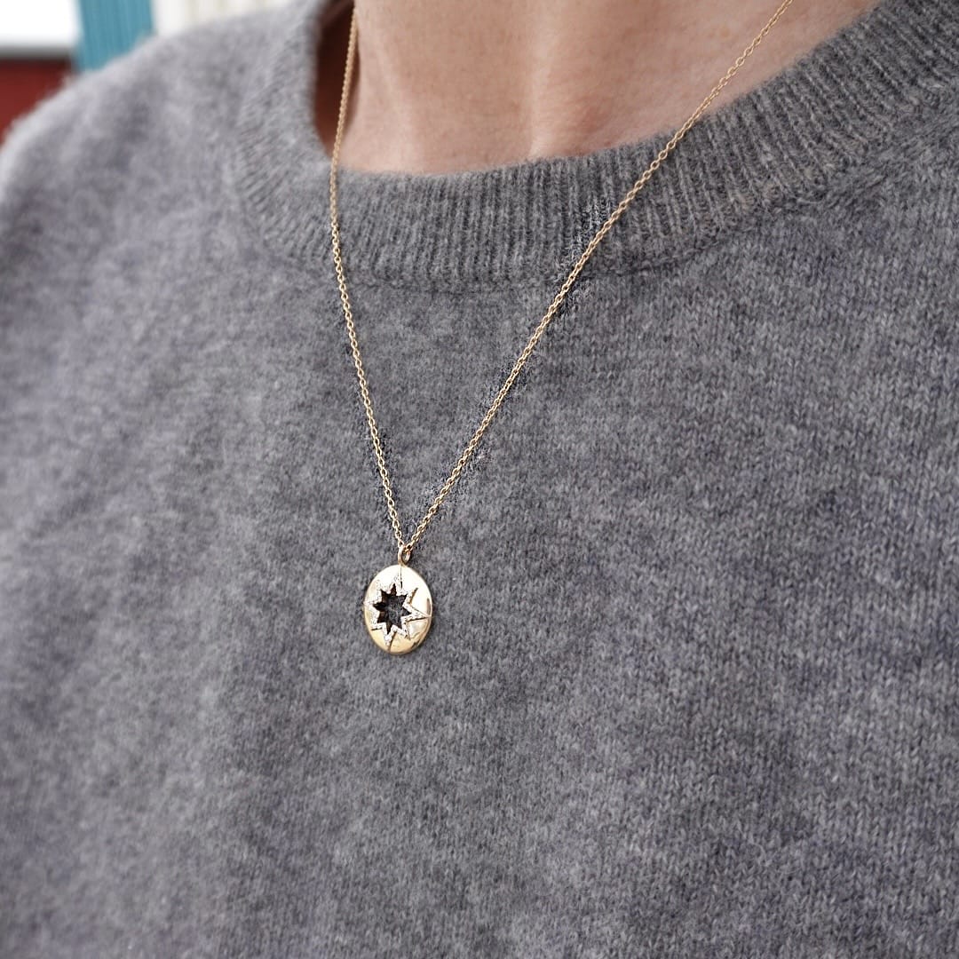 Gold necklace with a star pendant on a gray sweater