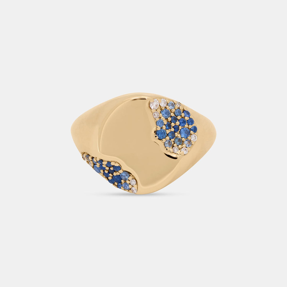 A gold signet ring featuring pavé blue sapphires and clear cubic zirconia stones on a light gray background.