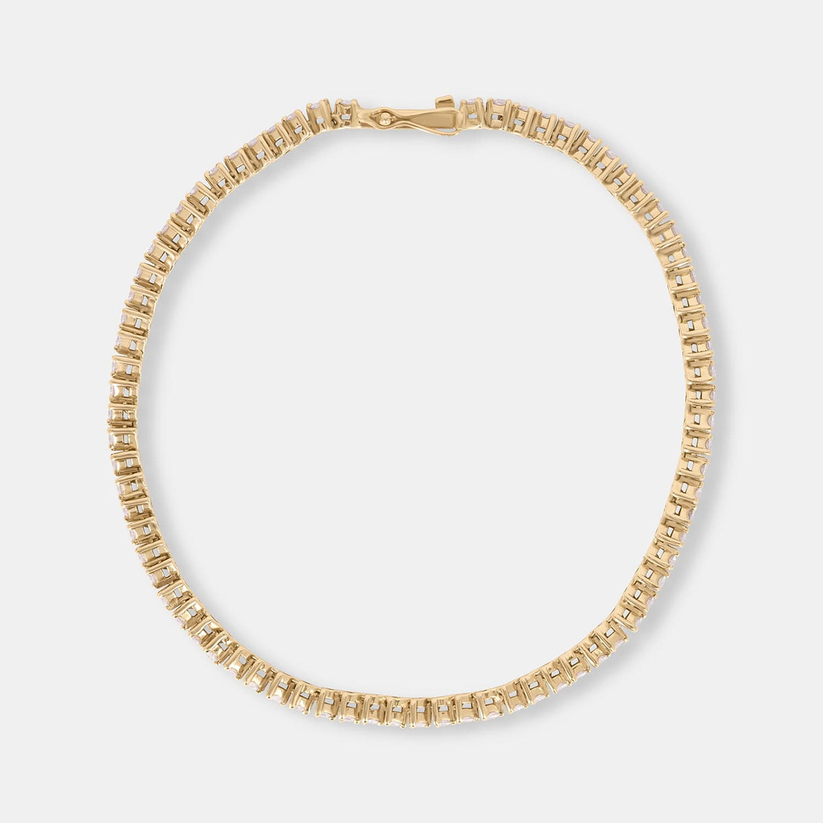 A gold tennis-style chain bracelet with arranged in an oval shape on a light gray background.
