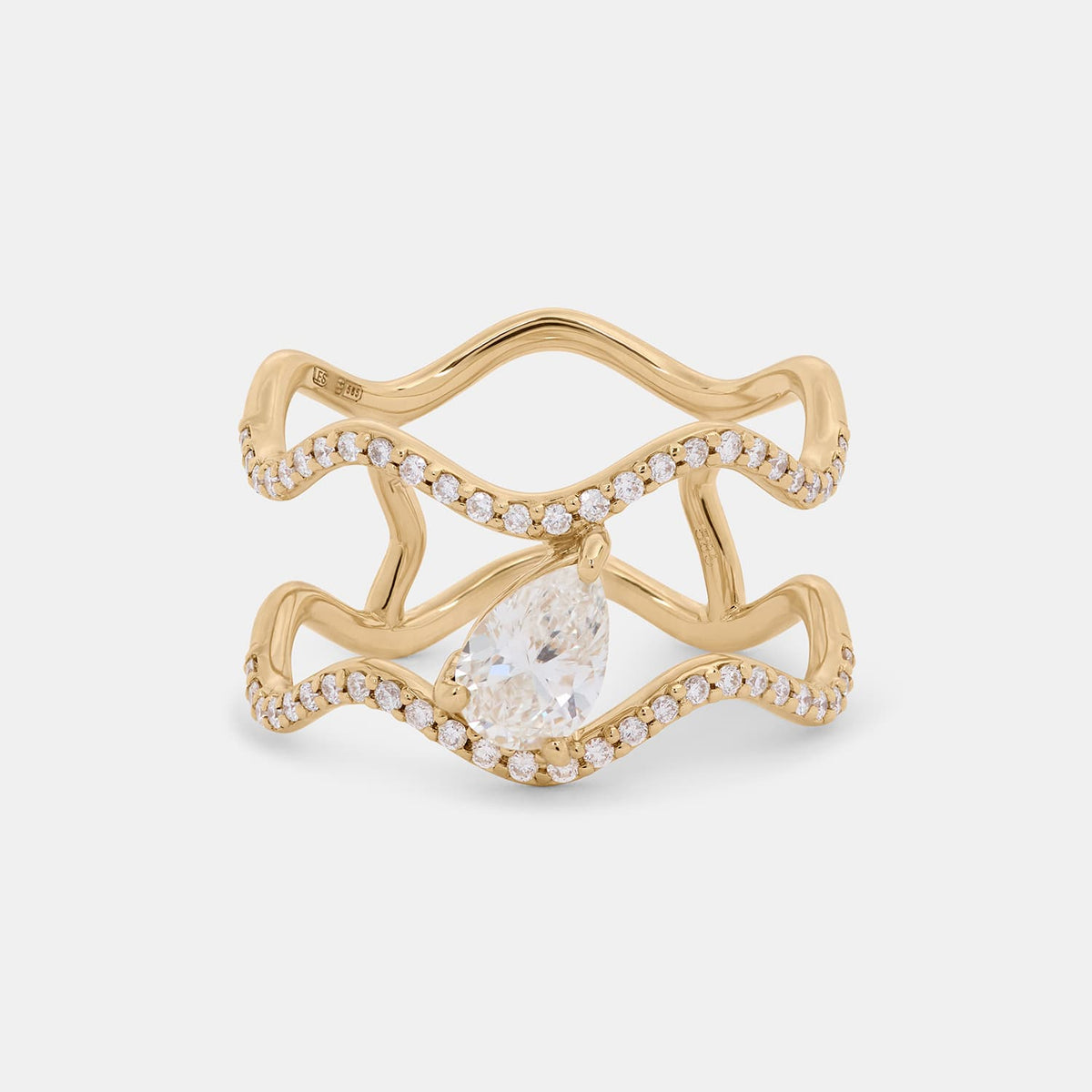 A gold wave-shaped ring with a large pear-cut clear center stone and rows of small clear stones along the curved bands, shown on a light gray background.