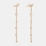 A pair of gold dangle earrings with clear gemstones, shown against a light gray background.