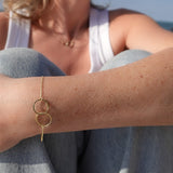 Close-up of a person's arm wearing a gold bracelet with interlocking rings.