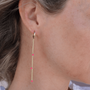 Gold earring with pink beads worn by a person