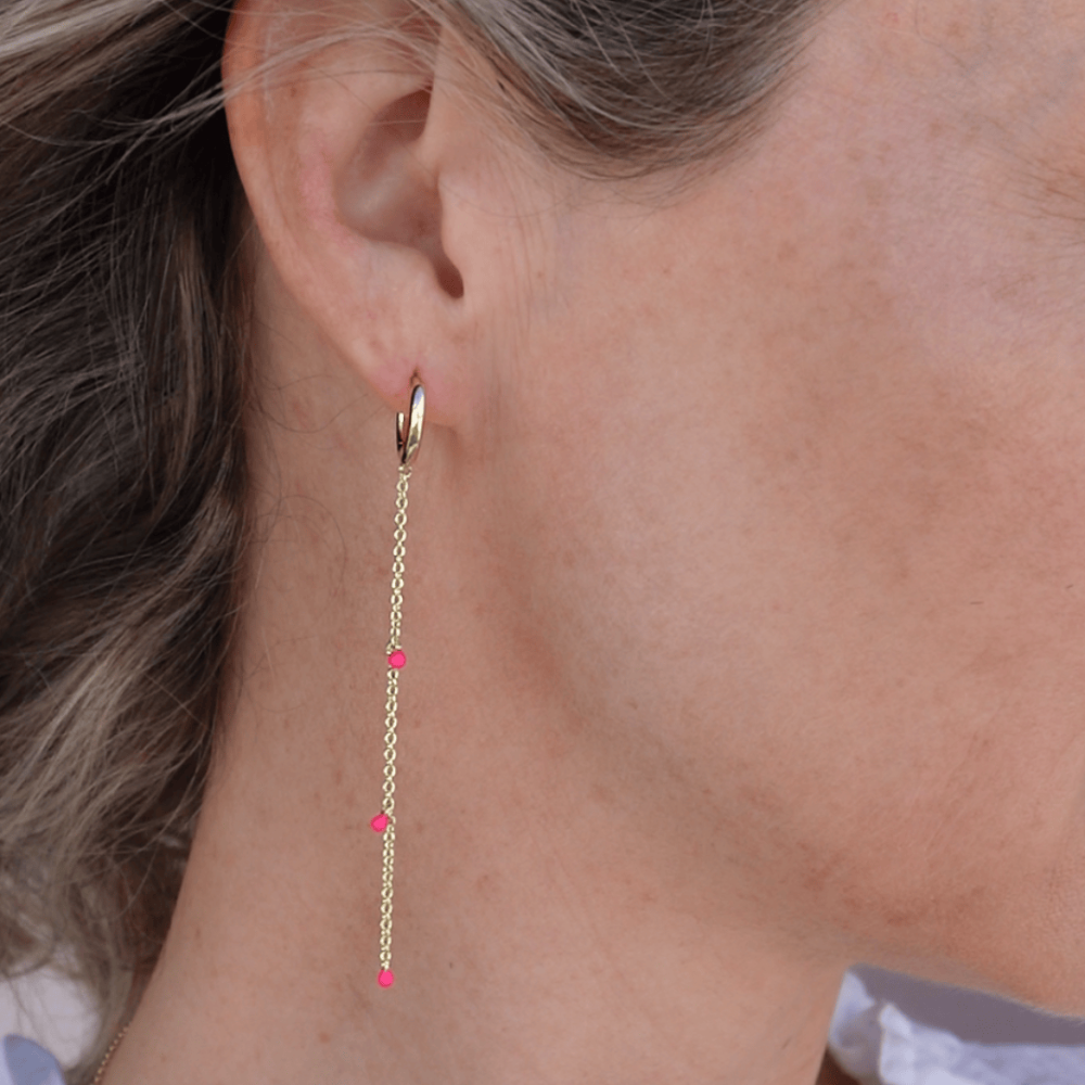 Gold earring with pink beads worn by a person