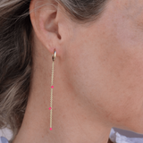 Gold earring with pink beads worn by a person