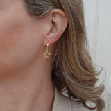 Close-up of a person wearing a gold star-shaped earring with a neutral background